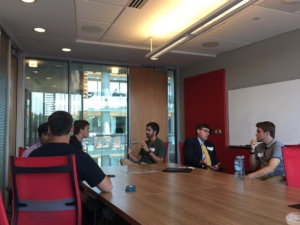 Students sitting around a table have a conversation.