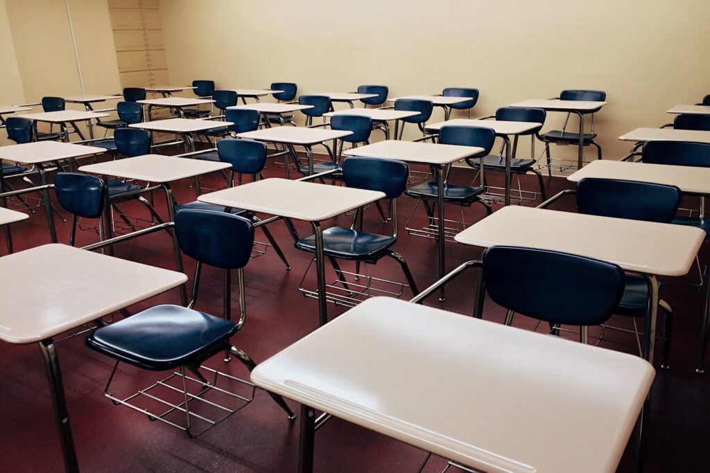 Empty school classroom. Yellow walls. Red floor. Blue and tan metal desks.