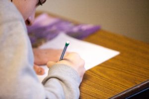 Student is hunched over a desk, taking a test